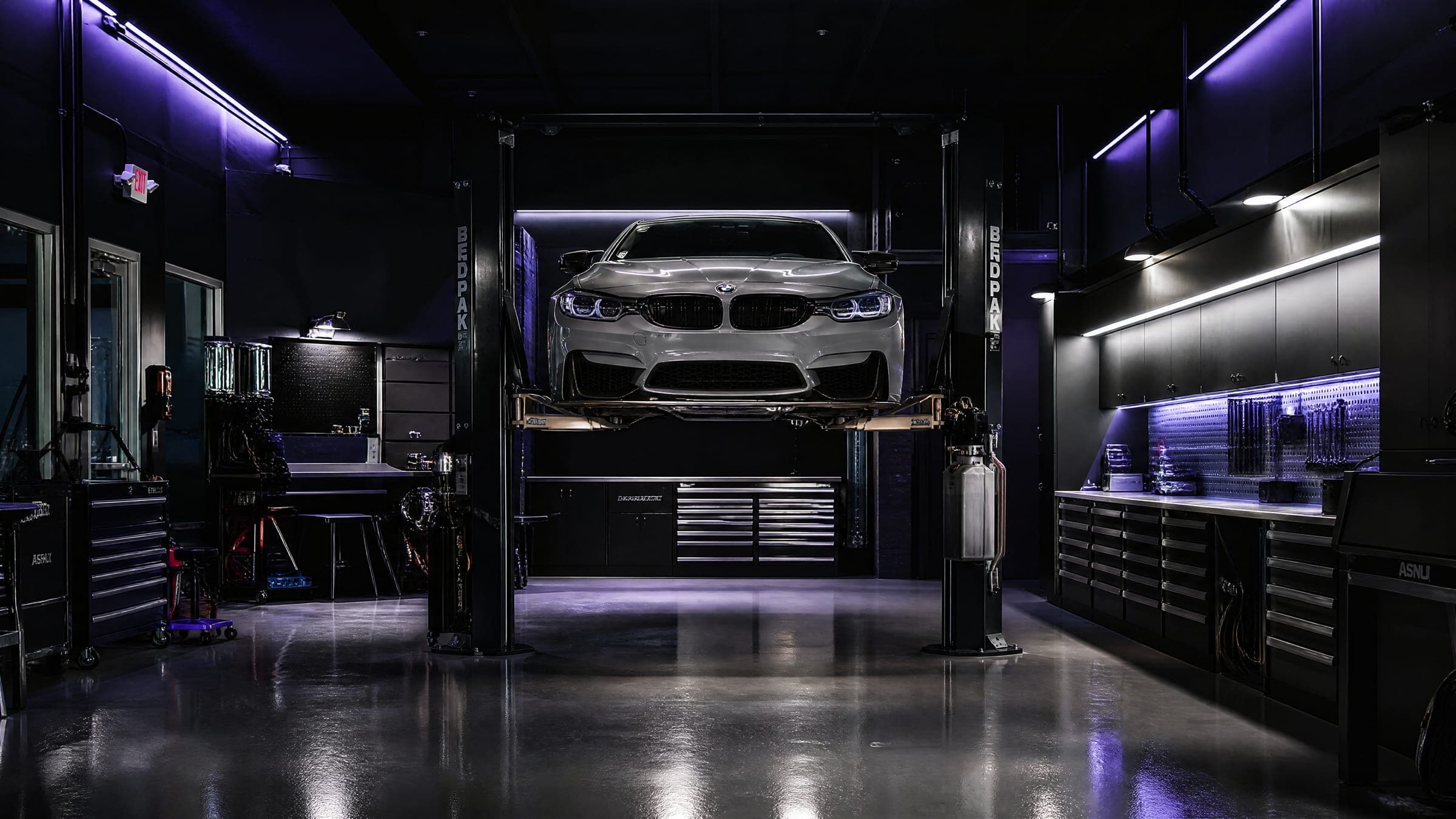 Inside the Elite workshop — a BMW M4 raised on the hoist under premium LED lighting